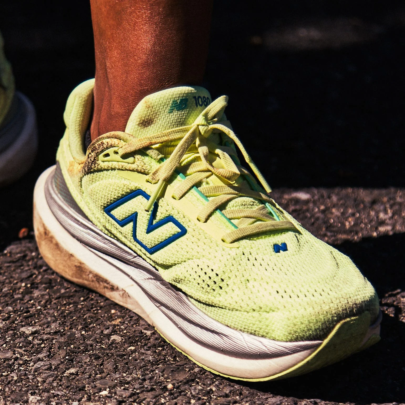 Bright yellow New Balance running shoes on a pavement surface.