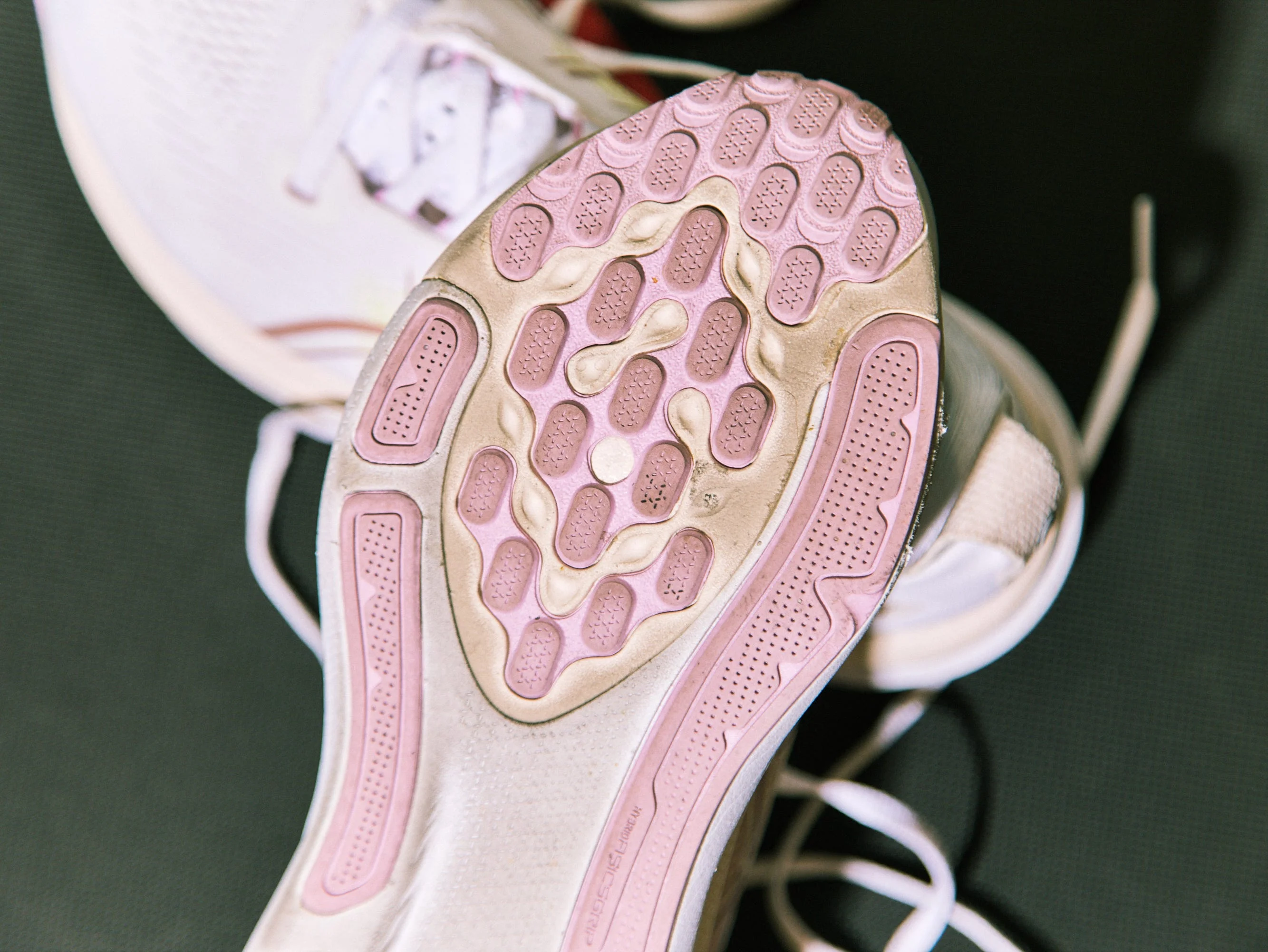 Close-up of the sole of a athletic shoe with textured grip patterns and laces in the background. Close-up of the sole of a athletic shoe with textured grip patterns and laces in the background.