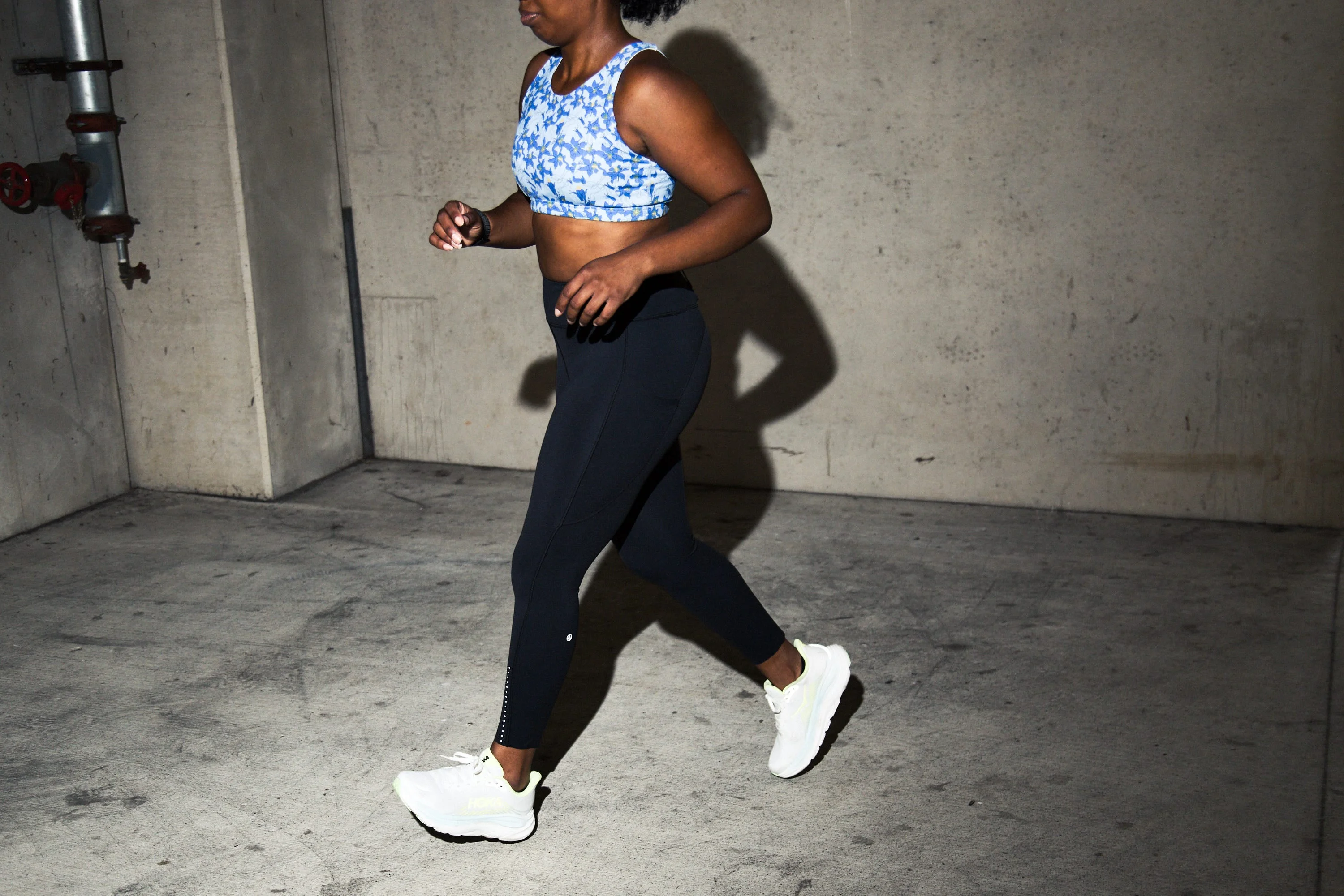 A person jogging in athletic wear against a concrete background. A person jogging in athletic wear against a concrete background.