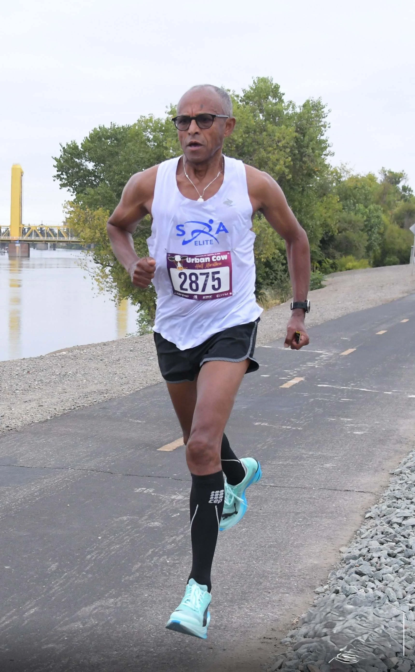Runner in athletic gear competing in a half marathon along a scenic path by the water.