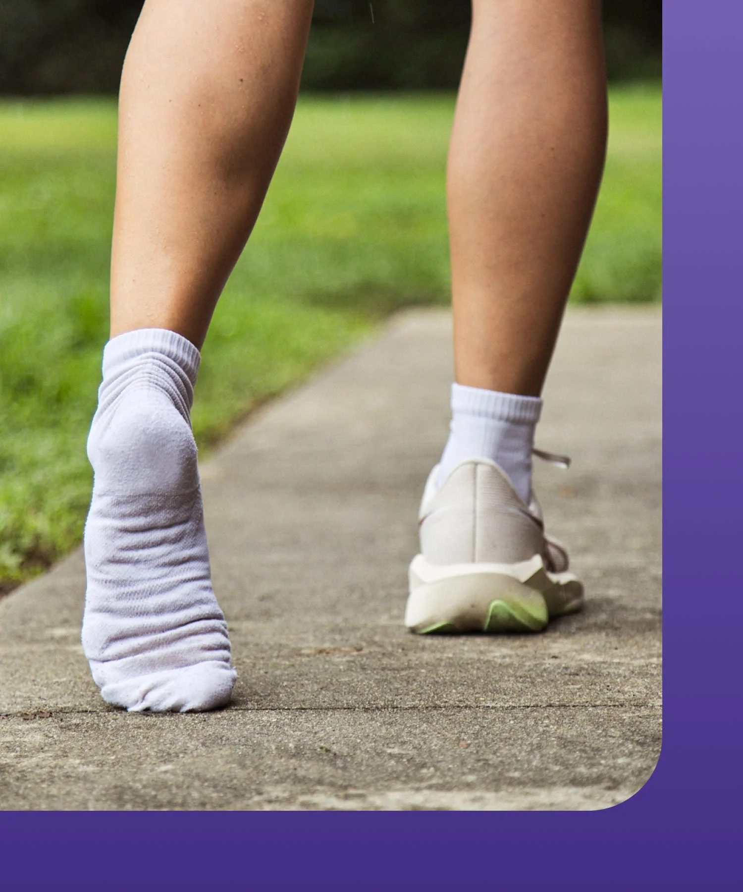 A person stretching foot on a path wearing one sock and one running shoe.