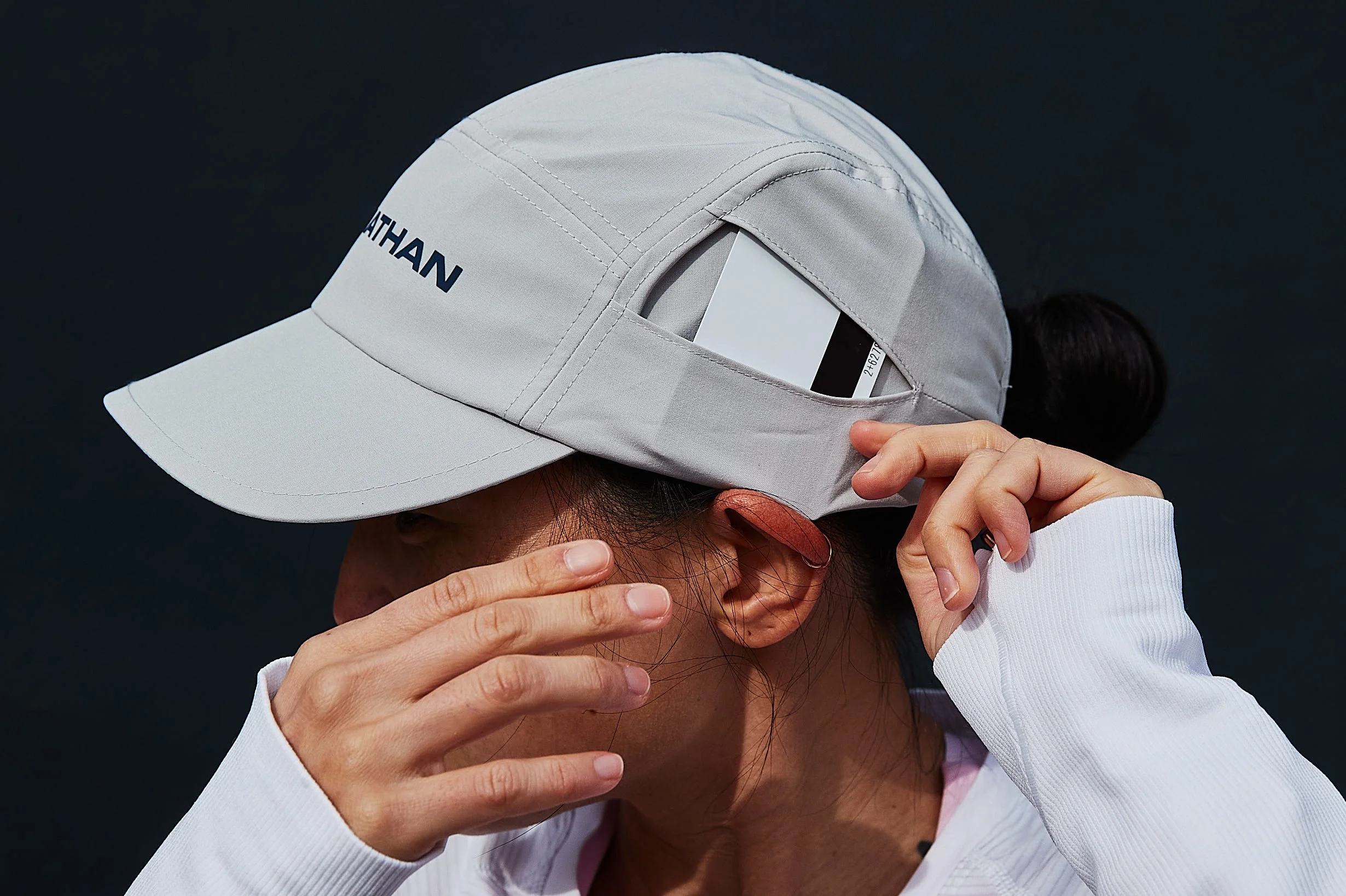 person adjusting a cap while wearing a white longsleeve shirt