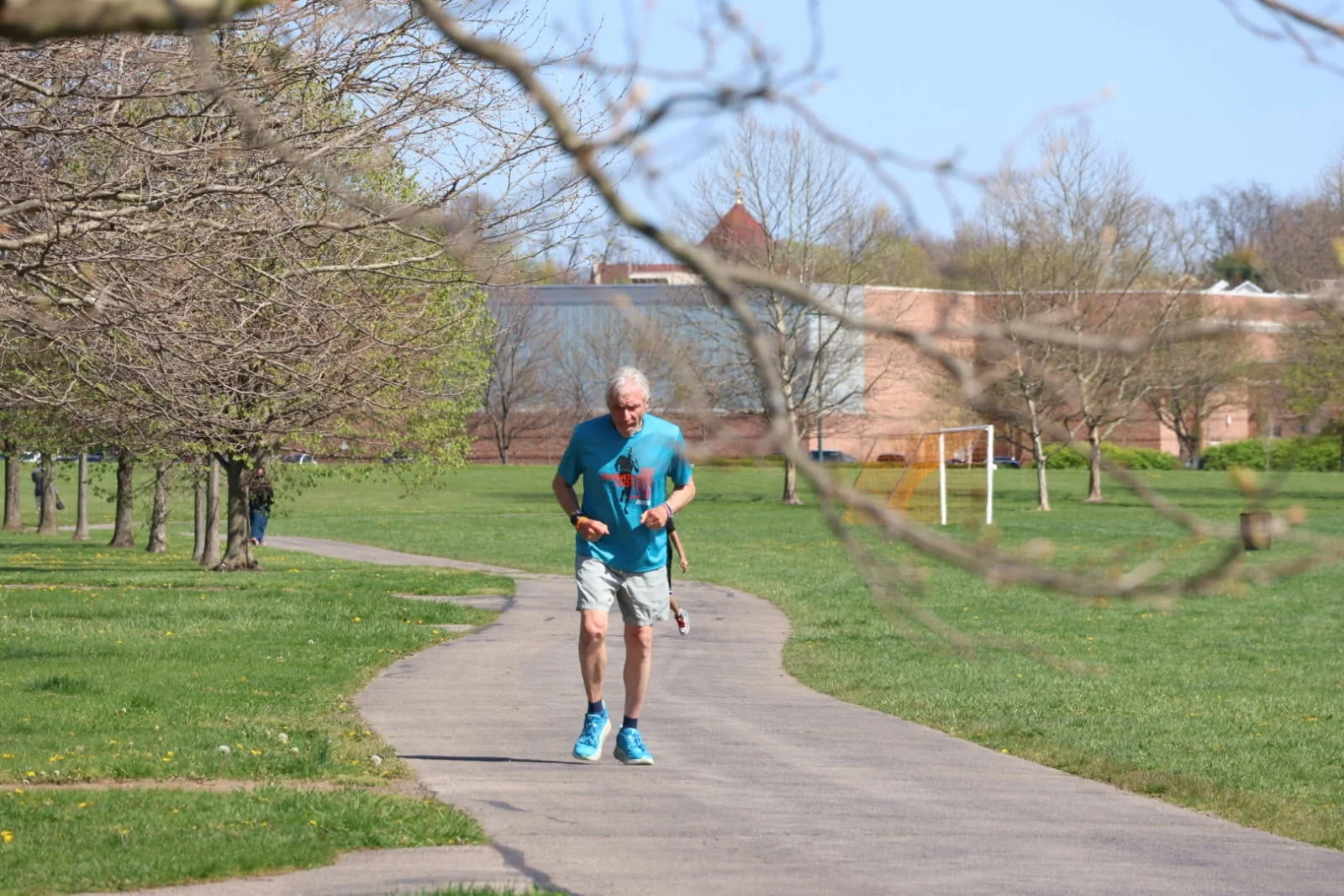 Person jogging on a park path surrounded by trees. Person jogging on a park path surrounded by trees.