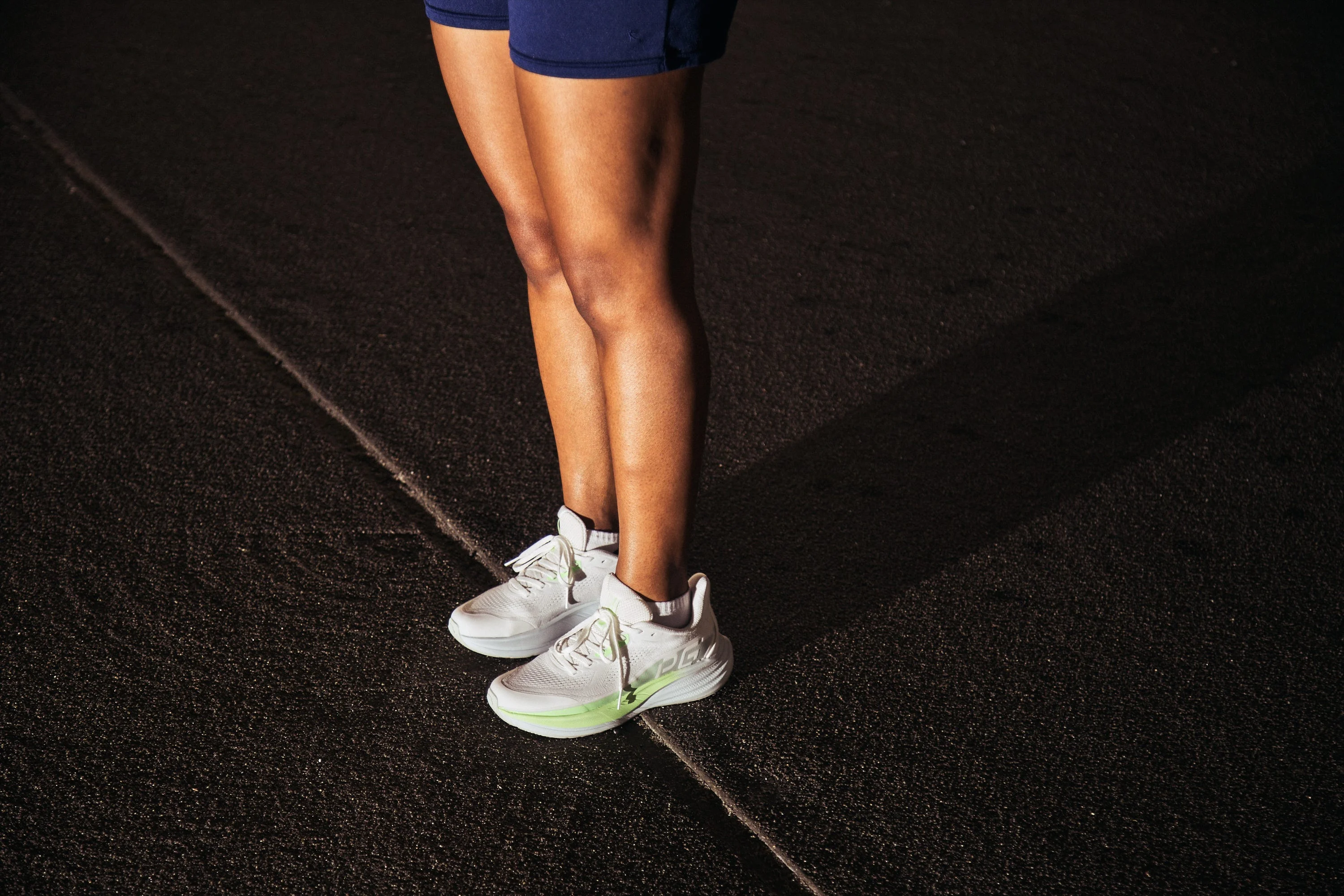 Person standing in athletic shoes on a dark road at night