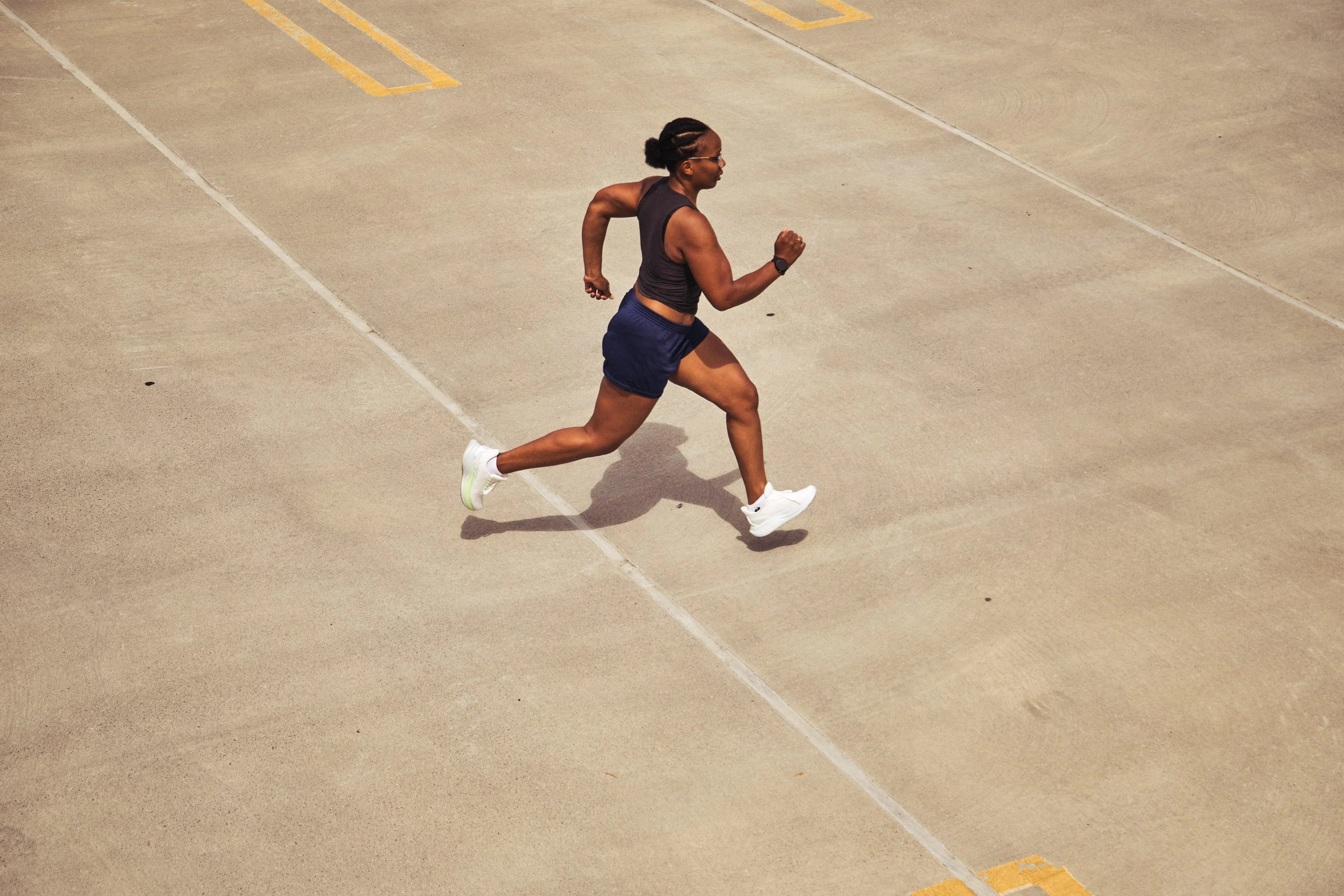 Person running on a concrete surface in athletic gear and white sneakers