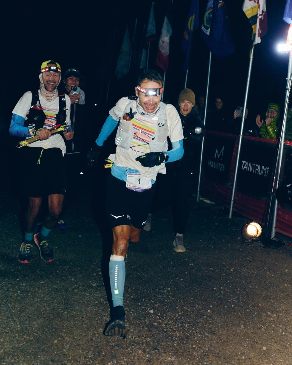 Runners crossing the finish line of a night race, celebrating their accomplishment amidst cheering spectators. Runners crossing the finish line of a night race, celebrating their accomplishment amidst cheering spectators.
